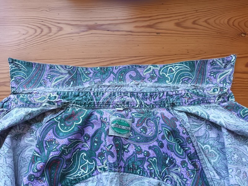 Nahaufnahme eines Hemdkragens einer bunt gemusterten Bluse. Die verschlissenen Stellen am Kragen sind deutlich zu sehen.