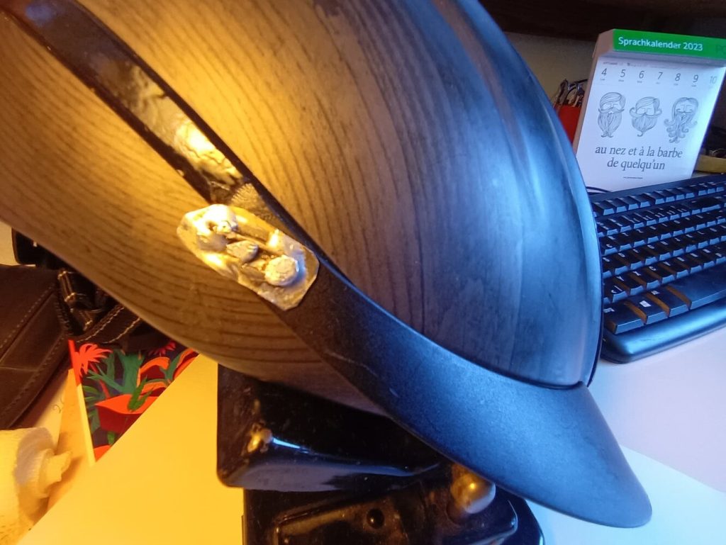 Nahaufnahme des Reithelms mit dem reparierten Bügel zum befestigen des Schirms am Helm.